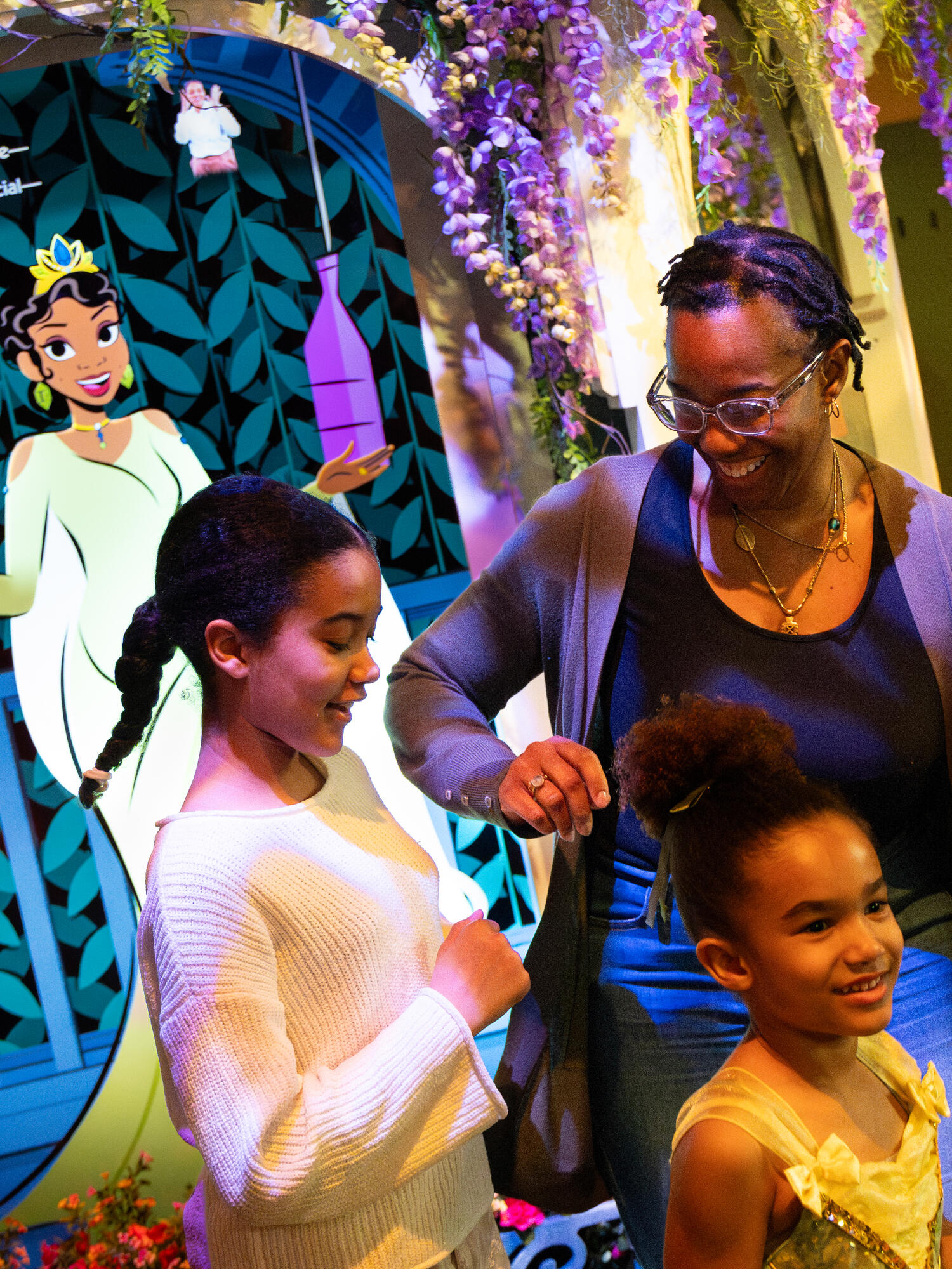 Family dancing in front of the Royal Float in the Tiana's Joyful Celebration exhibit.