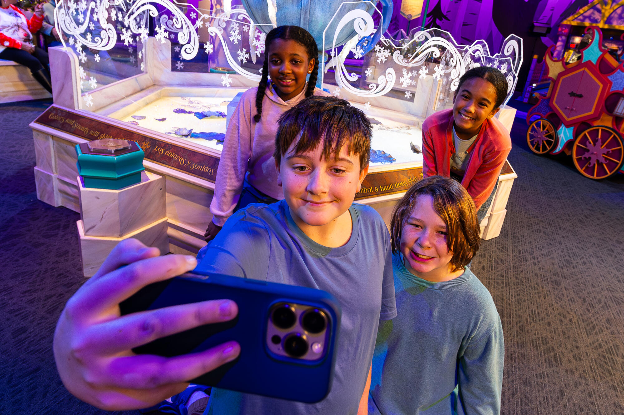 Children taking a selfie in front of the frozen fountain inside the WinterFaire exhibit.