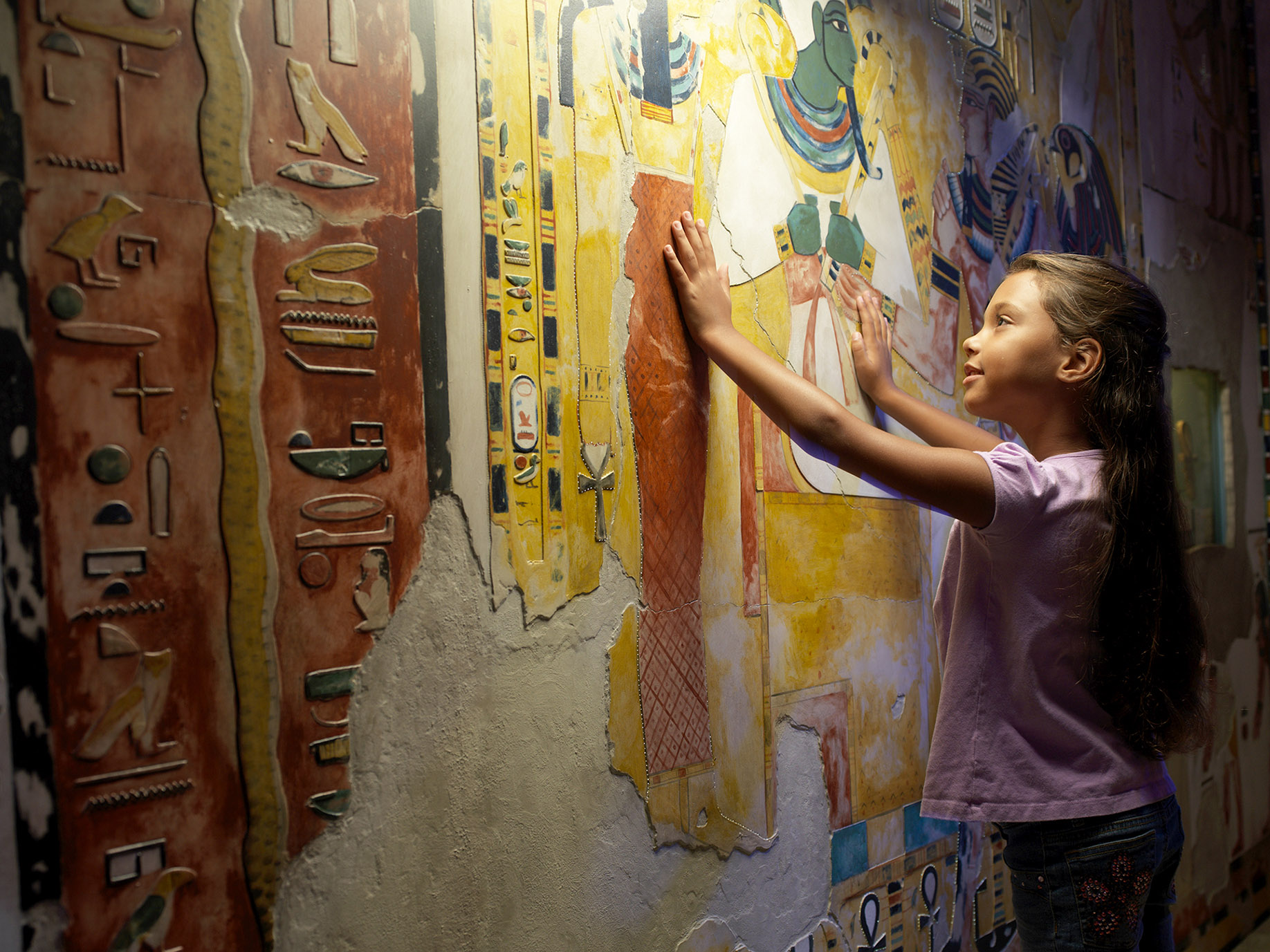 Child examining wall of hieroglyphics.