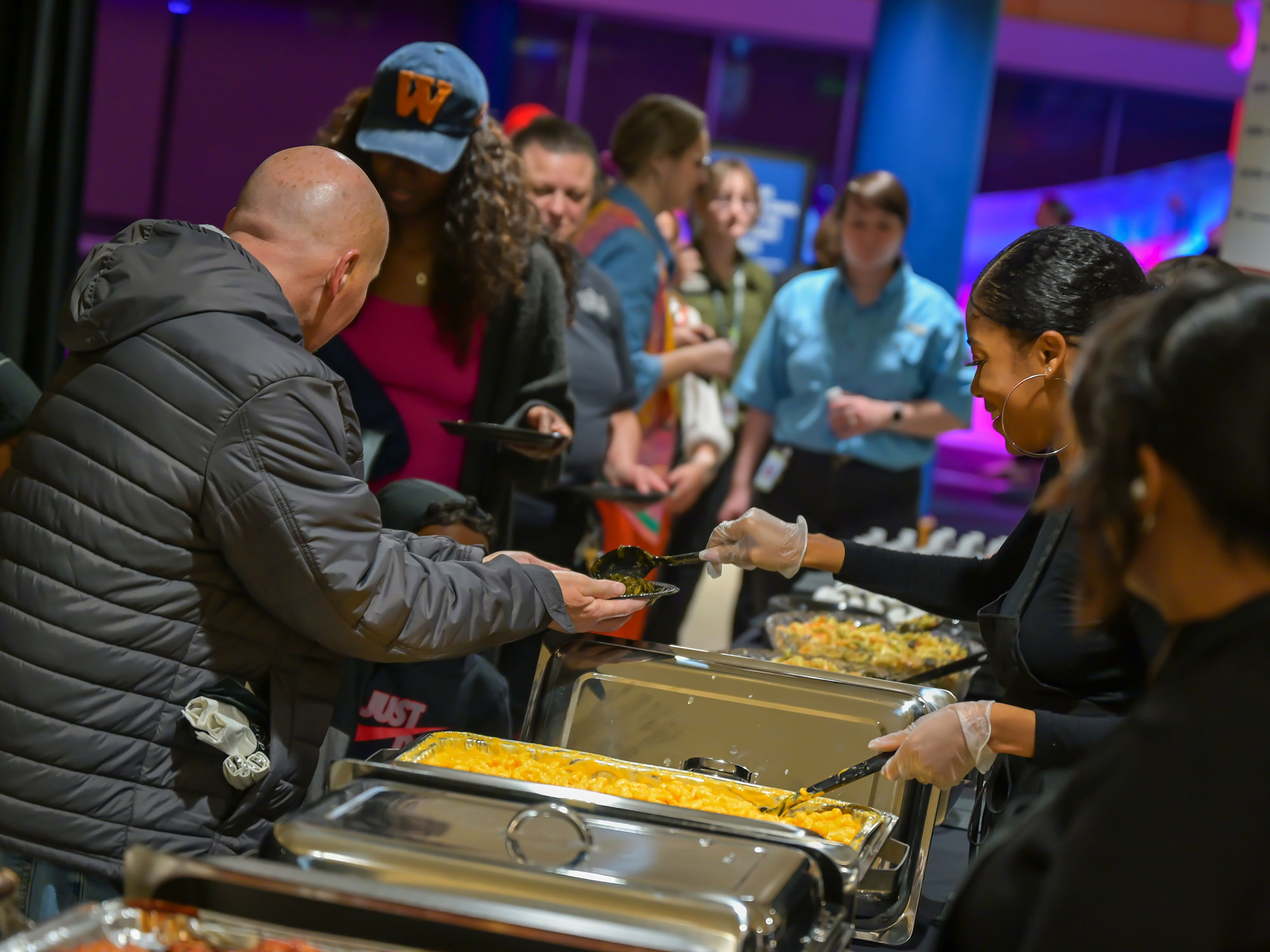 People in a buffet line getting food.