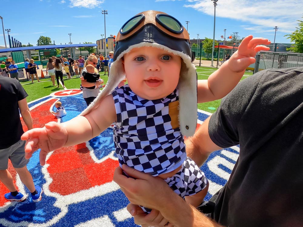 Baby wearing checkered flag-themed outfit in the Soccer Experience.