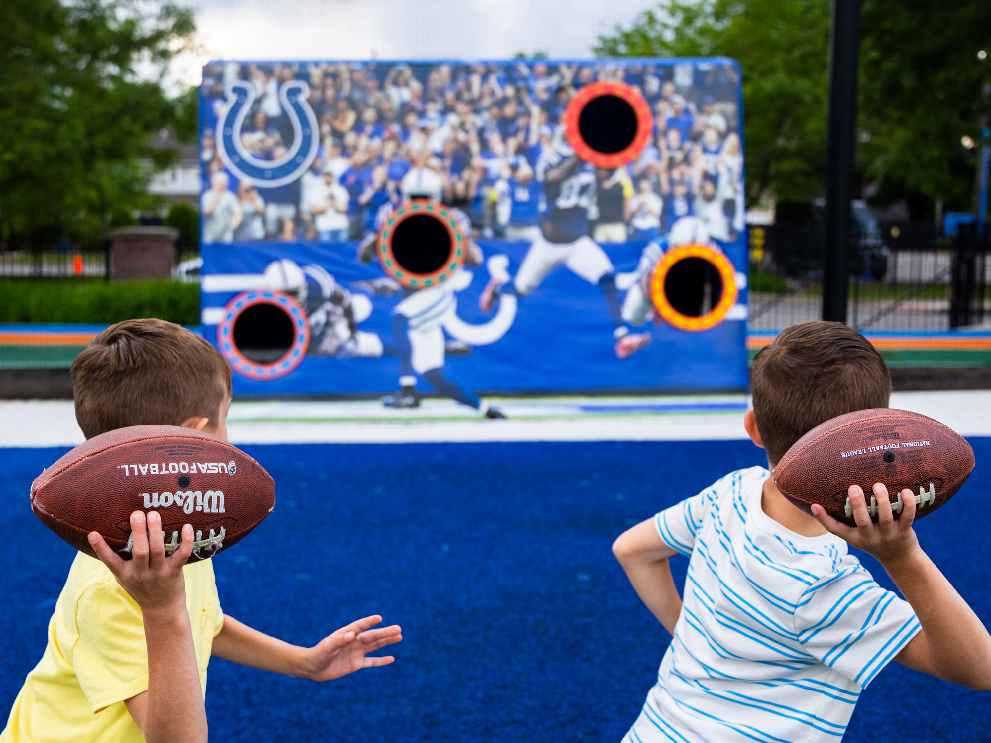 Two children throwing footballs towards an Indianapolis Colts cutout.