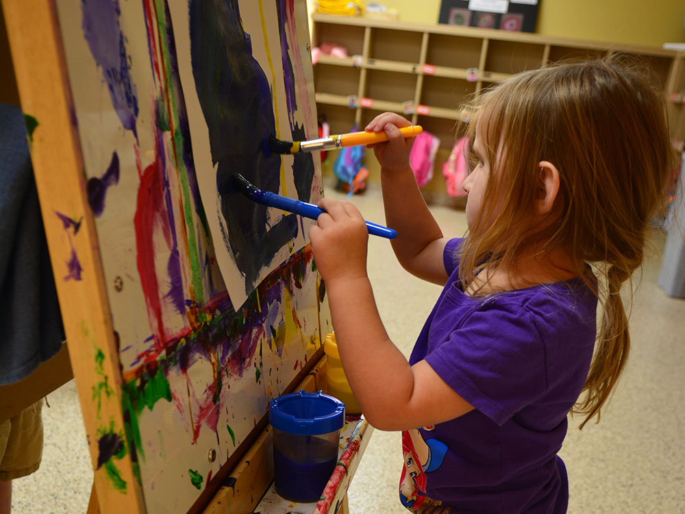 Child painting in a classroom in The Children's Museum Preschool at The Children's Museum of Indianapolis