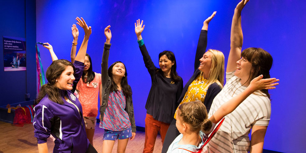 Group of people looking at each other, smiling, and raising their hands.