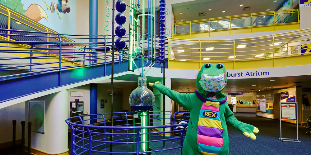 Rex standing in front of the Water Clock in the Sunburst Atrium at The Children's Museum of Indianapolis.