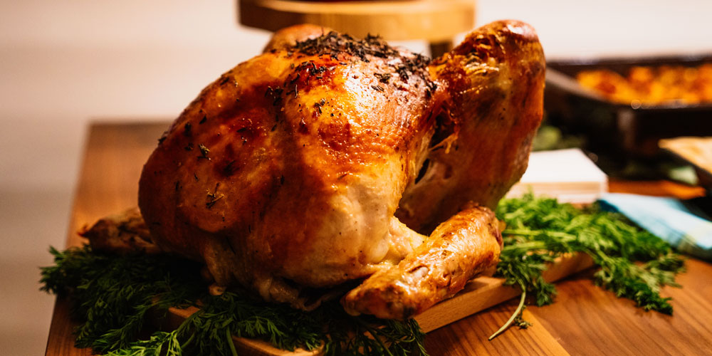 Roasted turkey sitting on a bed of green herbs.