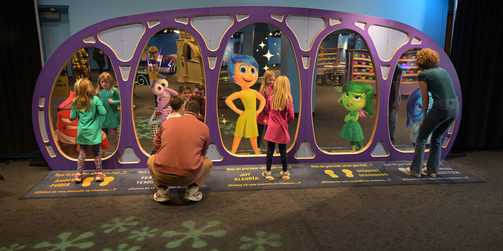 Family looking at their reflections with pictures of the emotion characters from Pixar's Inside Out.