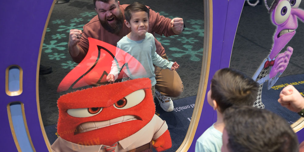 Grown-up and child making angry faces in a mirror with a picture of Anger from Pixar's Inside Out.