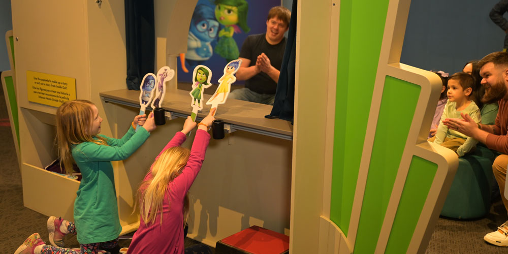 Children performing a puppet show with characters from Pixar's Inside Out.