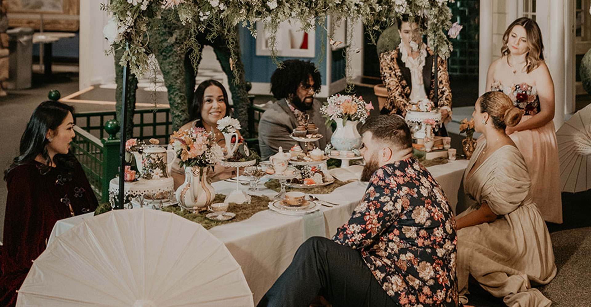 People sitting around a table set for a lavish picnic.