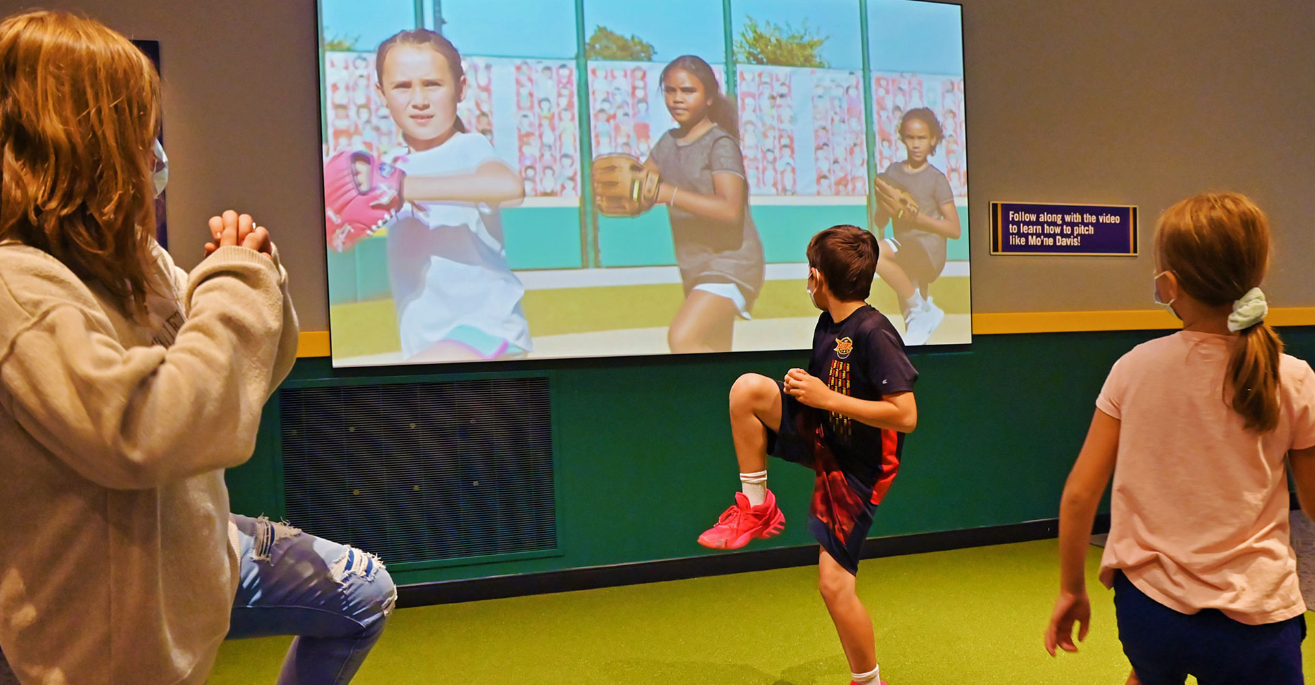 Children learning how to pitch in the Baseball Boundary Breakers exhibit.