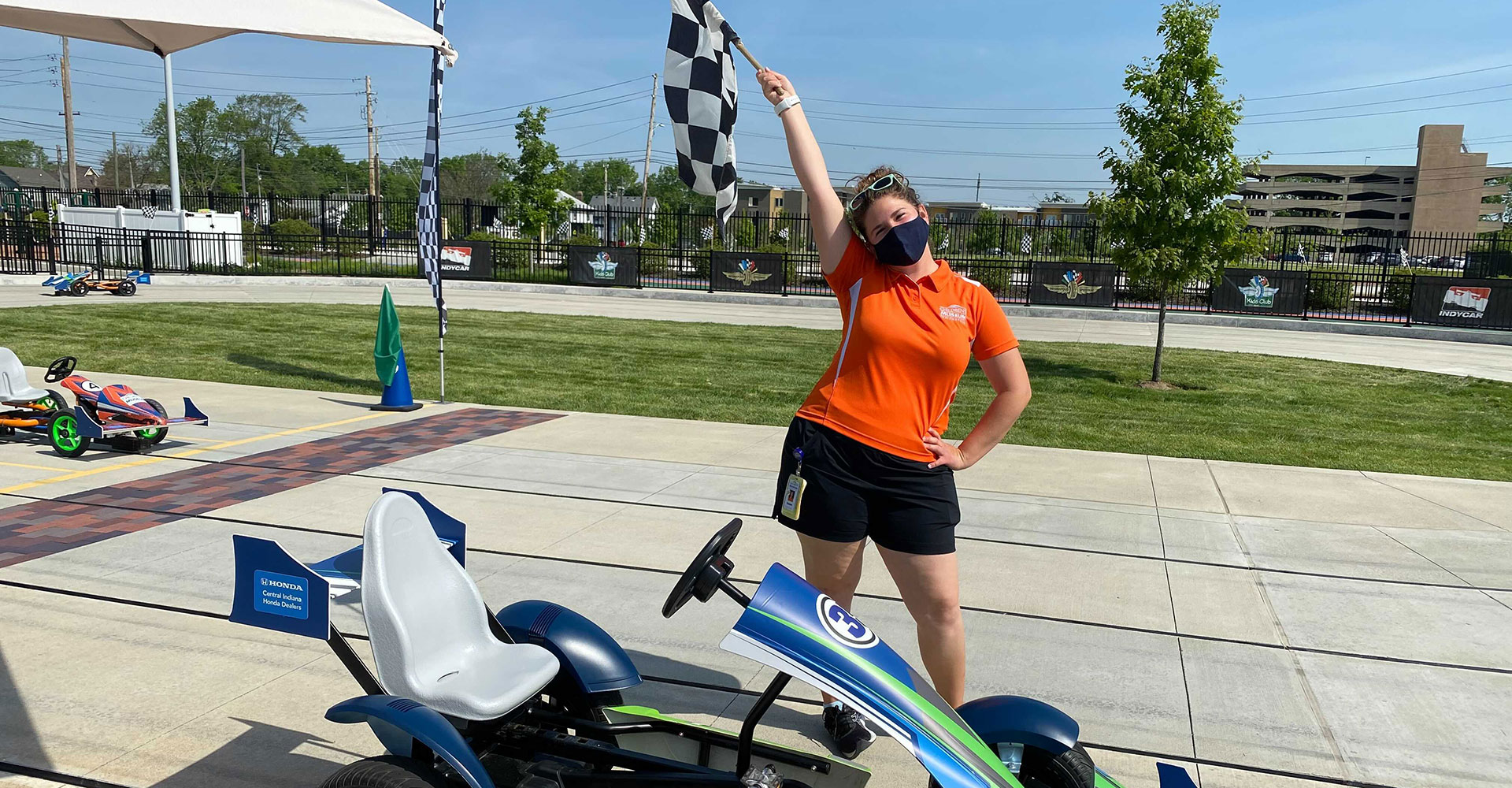 Riley Children's Health Sports Legends Experience coach Elizabeth waves a checkered flag in the Racing Experience at The Children's Museum of Indianapolis