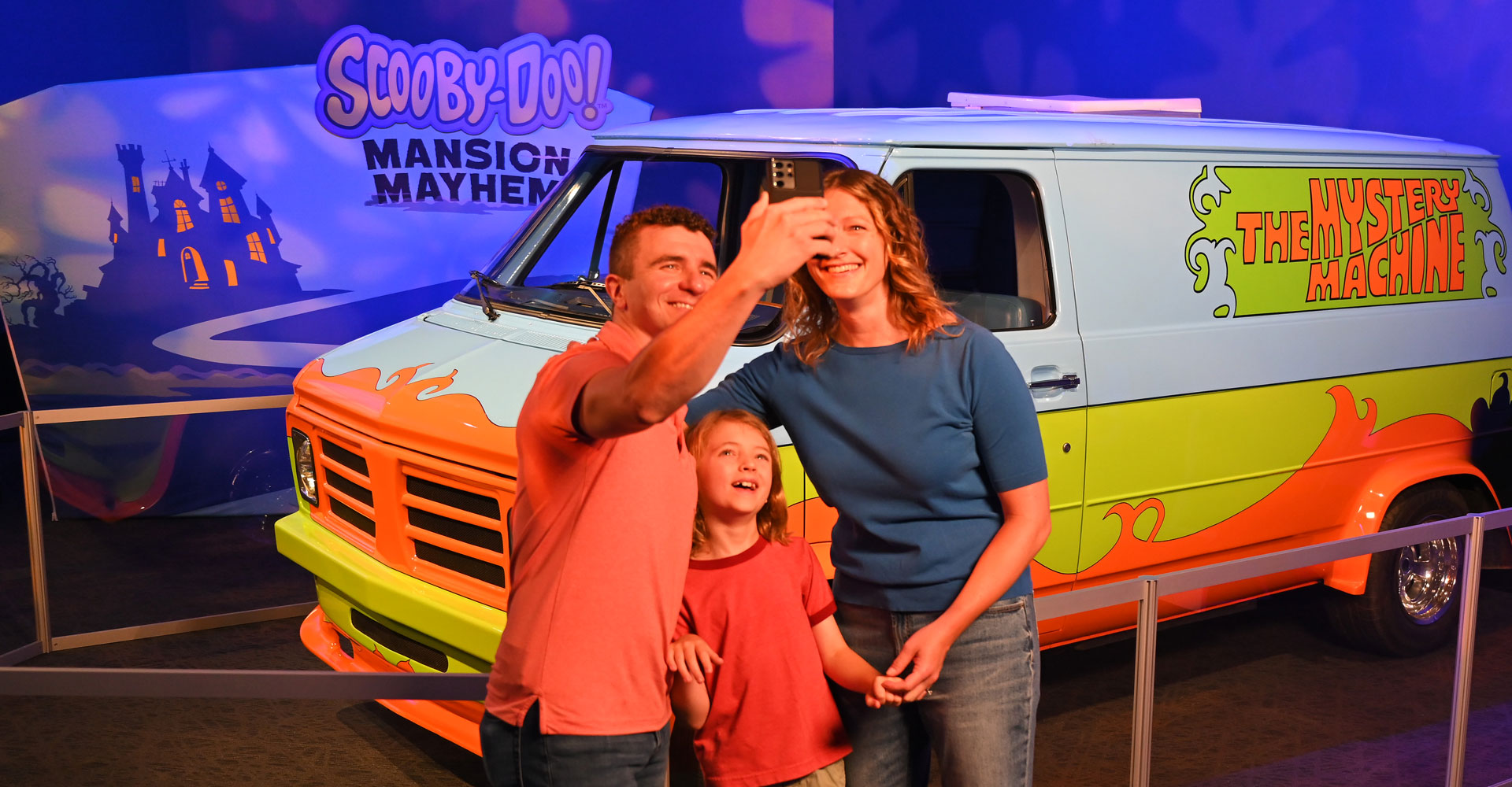 Family posing for a selfie in front of The Mystery Machine.