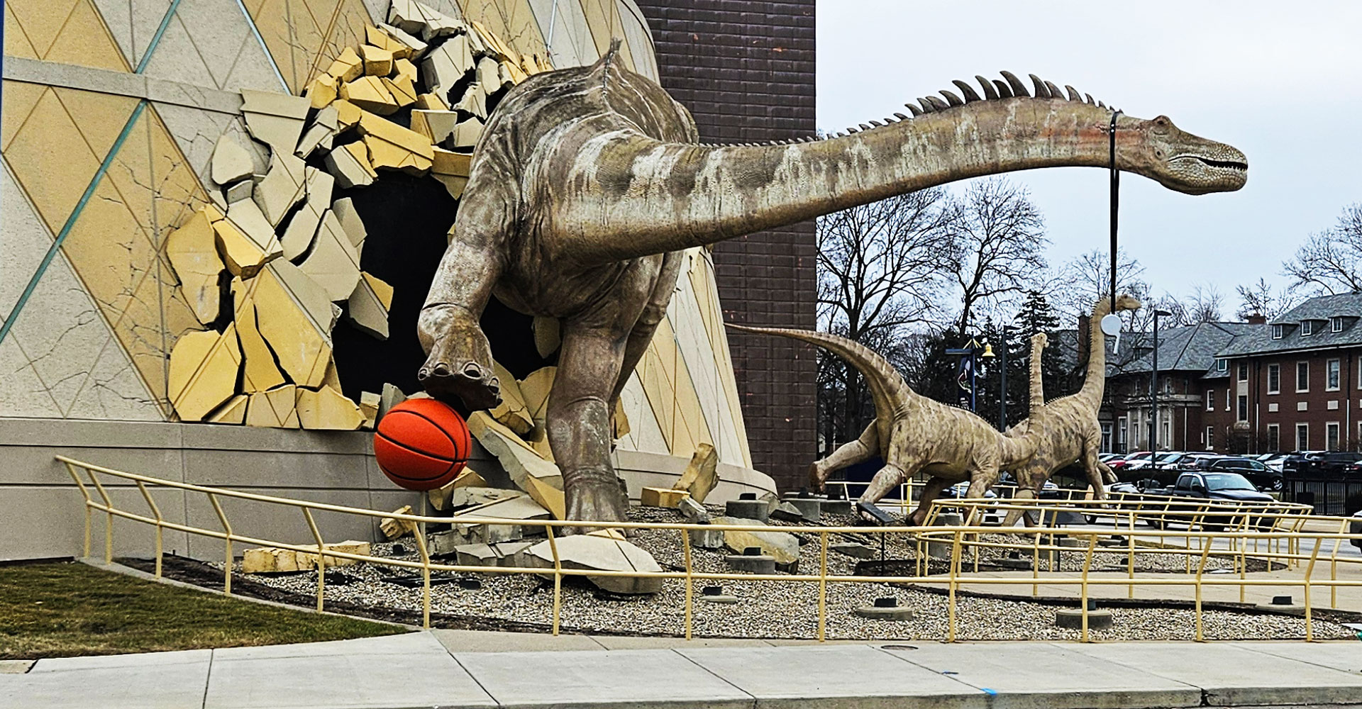 Sculpture of dinosaur bouncing a basketball and wearing a whistle.