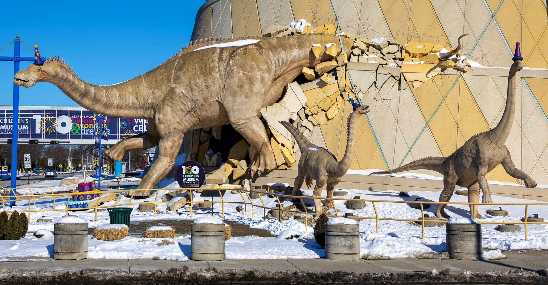 Sculpture of dinosaurs bursting out of the museum with a giant purple microphone and wearing Taylor Swift-inspired friendship bracelets.