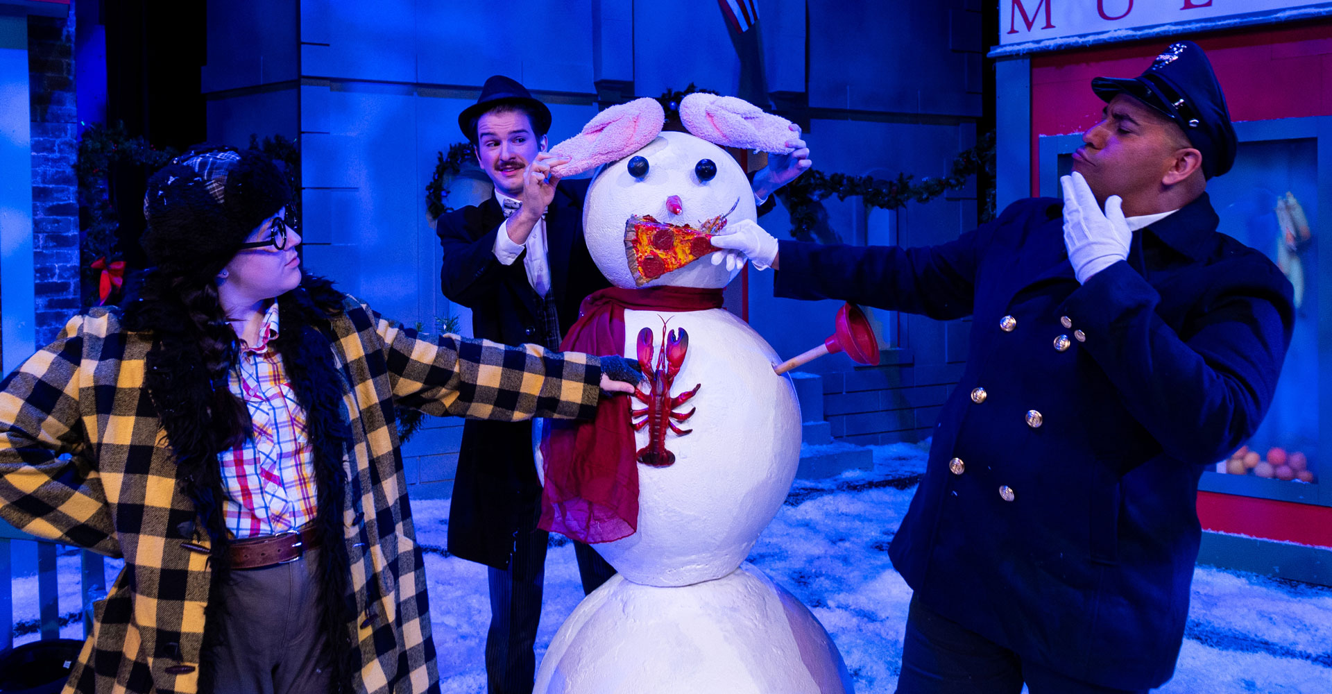 Three grown-ups laughing and playing with a snowman.