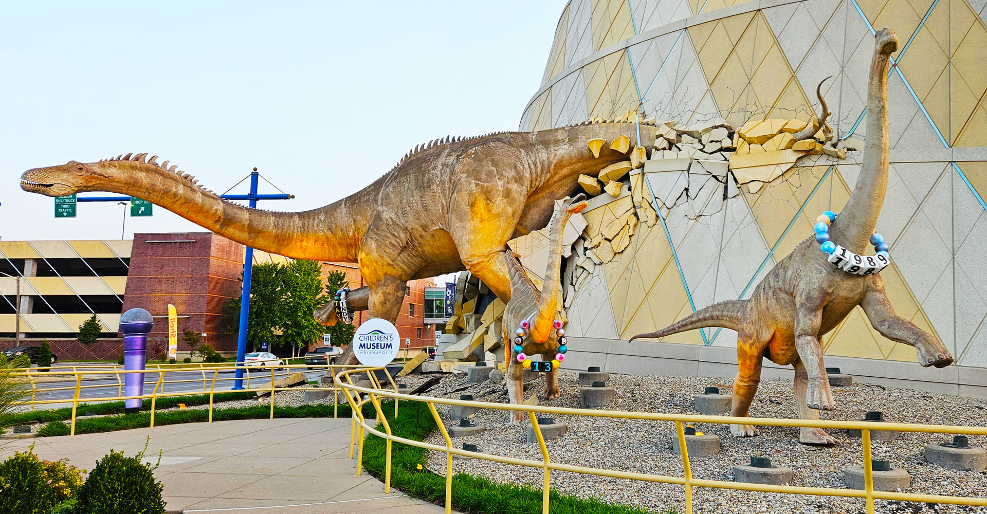 Sculpture of dinosaurs bursting out of the museum with a giant purple microphone and wearing Taylor Swift-inspired friendship bracelets.