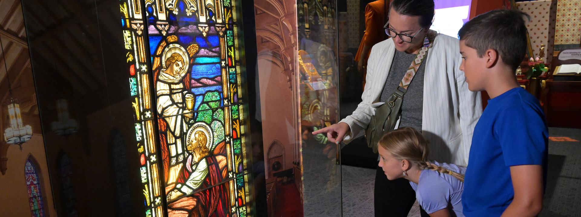 Family examining a stained glass window in the Sacred Places exhibit.