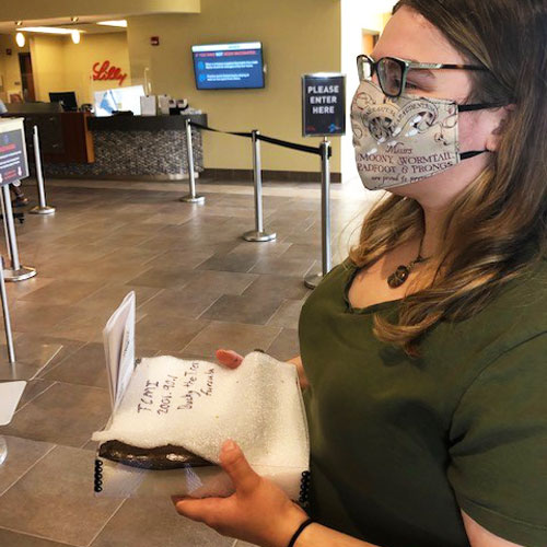 Paleontology Curator Laura Rooney holding Bucky's furcula in protective wrap while inside Eli Lilly and Company.