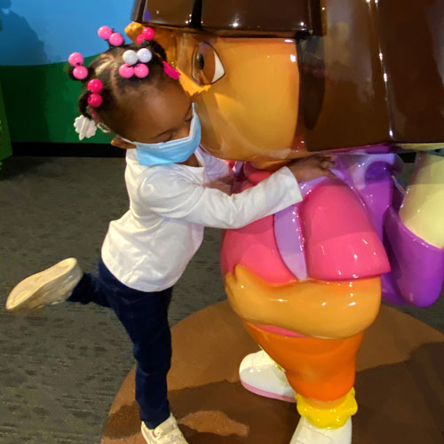 Child hugging a sculpture of Dora the Explorer inside the Dora and Diego—Let's Explore! exhibit at The Children's Museum of Indianapolis