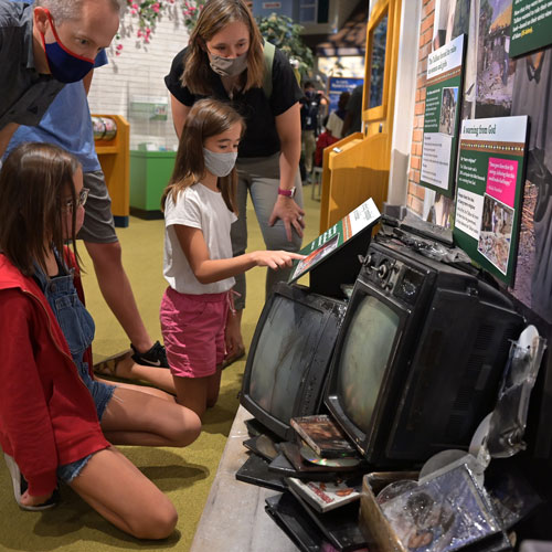 Family exploring a display about the Taliban in Pakistan inside the Malala area of The Power of Children exhibit.