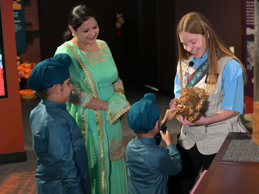 Grown-up and child examining an object with museum interpretive staff.