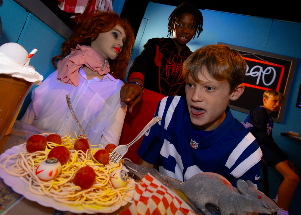 Children reacting to an eyeball on a plate of spaghetti and meatballs.